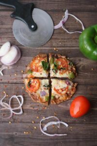 Pokrojona pizza z serka wiejskiego z boczkiem, żółtym serem i pomidorem przygotowana w air fryerze