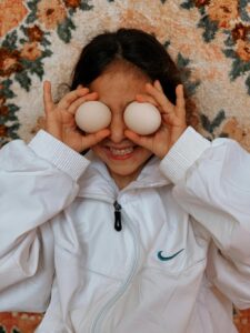 Kobieta z jajkami na oczach jako symbol domowej maseczki z białek jajek do pielęgnacji cery i włosów.